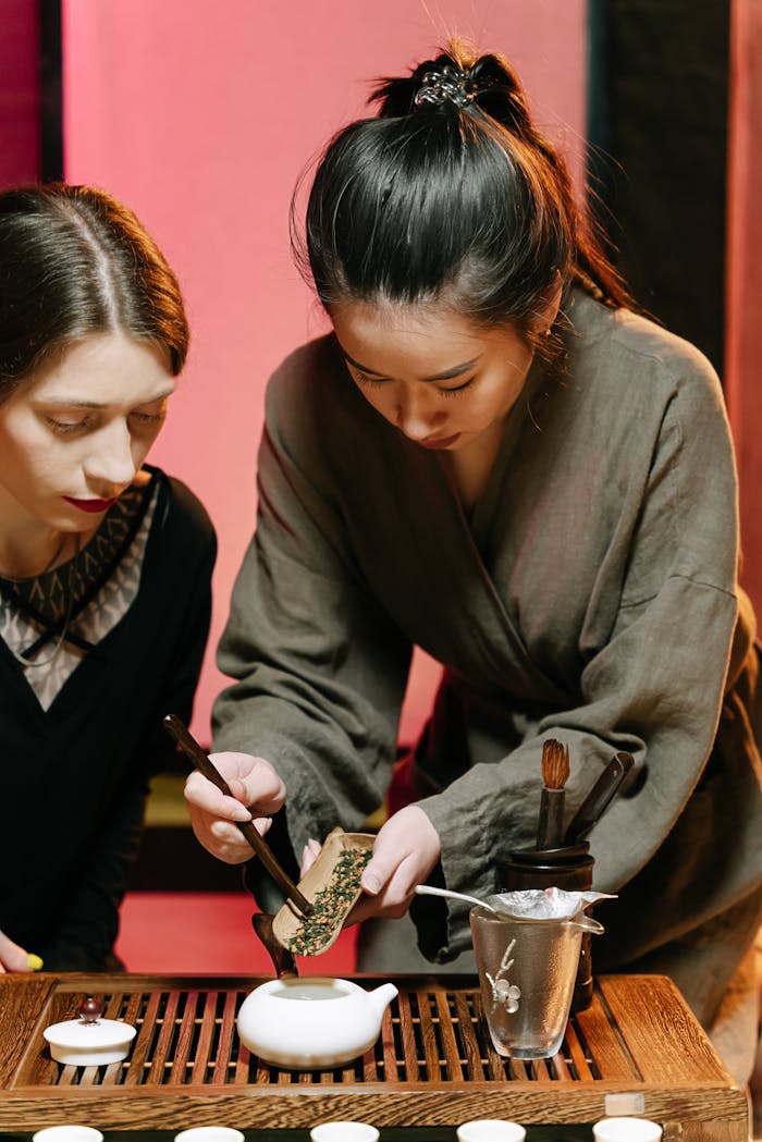 Two women participating in a traditional tea ceremony highlighting cultural attire and practices.